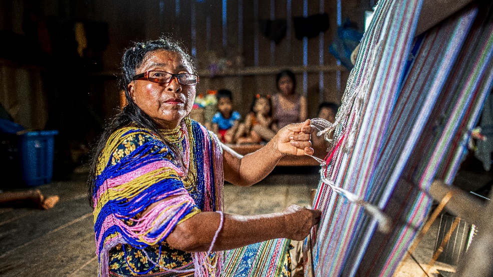Una mujer chachi tejiendo en una de las casas tradicionales